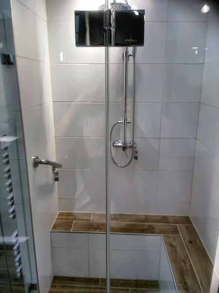 Prysznic walk-in z drewnianą ławką i deszczownicą