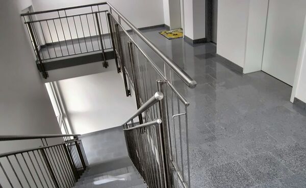 Schody z balustradą ze stali nierdzewnej i jasna posadzka